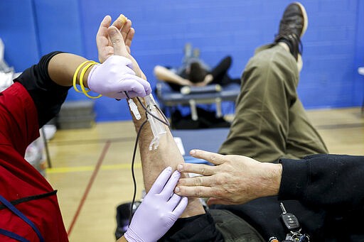 Nick Burruano, of Archbald, has his blood drawn by mobile phlebotomist Charmaine Metta during an American Red Ross blood drive a the Carbondale YMCA in Carbondale, Pa., on Thursday, March 26, 2020. Burruano was informed about a blood shortage partially due to the coronavirus.The American Red Cross reports a critical need of blood due the coronavirus. (Jake Danna Stevens/The Times-Tribune via AP)