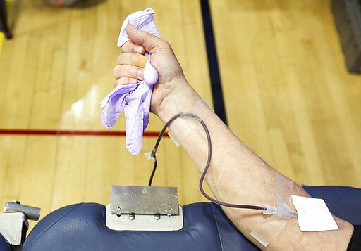 Gary Smith of Uniondale squeezes a glove to help blood flow from his arm as he donates blood during an American Red Cross blood drive at the Carbondale YMCA in Carbondale, Pa., on Thursday, March 26, 2020. The American Red Cross reports a critical need of blood due the coronavirus. (Jake Danna Stevens/The Times-Tribune via AP)