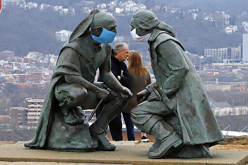 People take in the view of downtown Pittsburgh from Mount Washington with protective masks adorning the &quot;Point of View&quot; sculpture depicting George Washington and Seneca leader Guyasuta, Friday, March 27, 2020. (AP Photo/Gene J. Puskar)