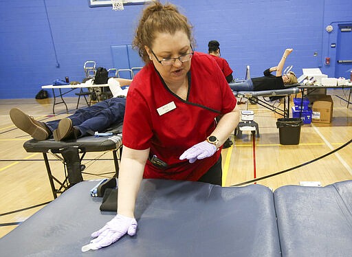 American Red Cross mobile phlebotomist April Evanitus sanitizes a bed during a blood drive at the Carbondale YMCA in Carbondale, Pa., on Thursday, March 26, 2020. The American Red Cross reports a critical need of blood due the coronavirus. (Jake Danna Stevens/The Times-Tribune via AP)