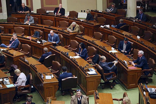 Lawmakers practice social distancing, Thursday, March 26, 2020 at the State Capitol in St. Paul, Minn. before the body met to take up bills related to the coronavirus in the state. A limited number of members were allowed on the House floor. The new coronavirus causes mild or moderate symptoms for most people, but for some, especially older adults and people with existing health problems, it can cause more severe illness or death. (AP Photo/Jim Mone)