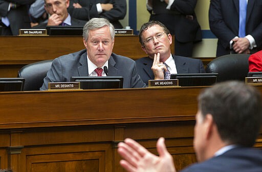 In this file photo from Thursday, July 7, 2016, Rep. Mark Meadows, R-N.C., left, and Rep. Thomas Massie, R-Ky., listen to FBI Director James Comey during a House Oversight Committee hearing at the Capitol in Washington. Meadows, currently President Donald Trump's acting-chief of staff, is still the sitting representative of North Carolina's 11th Congressional District in the House of Representatives as the body prepares to vote on massive relief funding to fight the Covid-19 pandemic, Friday, March 27, 2020. Party leaders had hoped to pass the measure by voice vote without lawmakers having to take the risk of traveling to Washington, but that plan might be complicated by Massie who could force a roll call vote. (AP Photo/J. Scott Applewhite, file)