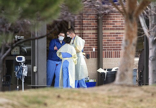 FILE - In this March 23, 2020, file photo donned in personal protective equipment, medical personnel work outside of St. Luke's Magic Valley's quick care entrance in Twin Falls, Idaho. State health officials say three Idaho residents have become the first reported deaths in the state because of COVID-19, the illness caused by the coronavirus. The officials said Thursday, March 26, 2020, that two of the cases were in Blaine County. One was a man over the age of 60 and the other was a man over the age of 80. It wasn't clear if either had underlying health issues. (Drew Nash/Times-News via AP, File)