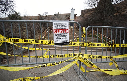 Barriers stand covered with caution tape at a set of stairs leading to Red Rocks Amphitheatre during a statewide stay-at-home order in an effort to reduce the spread of the new coronavirus Friday, March 27, 2020, in Morrison, Colo. The new coronavirus causes mild or moderate symptoms for most people, but for some, especially older adults and people with existing health problems, it can cause more severe illness or death. (AP Photo/David Zalubowski)