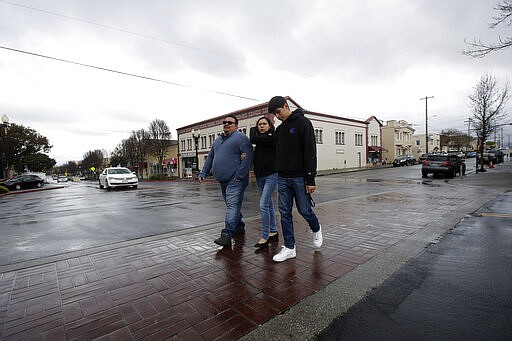 In this Tuesday, March 24, 2020, photo, William Gonzalez, from left, walks with his wife, Sonia Bautista, and their son Ricardo Bautista, 14, as they walk while being interviewed in South San Francisco, Calif. California's Bay Area has been shut down for more than a week, the first region of America to order its residents to stay home, work remotely and homeschool their children in a desperate bid to slow the spread of the coronavirus pandemic. (AP Photo/Jeff Chiu)