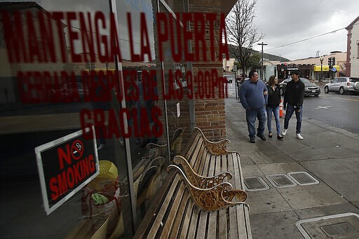 In this Tuesday, March 24, 2020, photo, William Gonzalez, from left, walks with his wife, Sonia Bautista, and their son Ricardo Bautista, 14, as they walk while being interviewed in South San Francisco, Calif. California's Bay Area has been shut down for more than a week, the first region of America to order its residents to stay home, work remotely and homeschool their children in a desperate bid to slow the spread of the coronavirus pandemic. (AP Photo/Jeff Chiu)