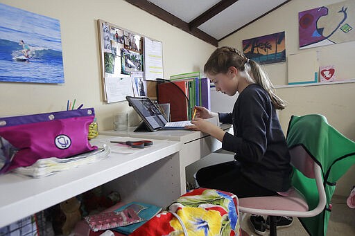 In this Thursday, March 19, 2020, photo, Rachel Keenan, 9, takes a live class online at her home in San Francisco. California's Bay Area has been shut down for more than a week, the first region of America to order its residents to stay home, work remotely and homeschool their children in a desperate bid to slow the spread of the coronavirus pandemic. (AP Photo/Jeff Chiu)