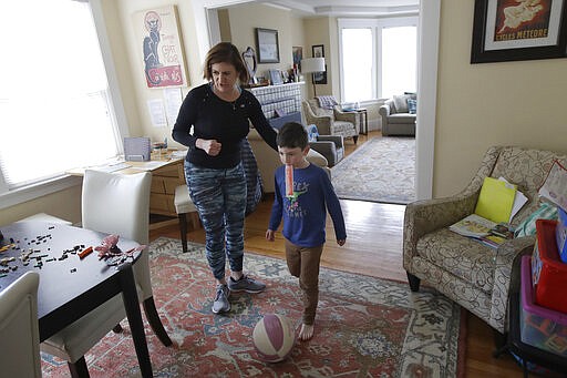 In this Thursday, March 19, 2020, photo, Rebecca Biernat gets her son Seamus Keenan, 6, ready to take a live class online at their home in San Francisco. California's Bay Area has been shut down for more than a week, the first region of America to order its residents to stay home, work remotely and homeschool their children in a desperate bid to slow the spread of the coronavirus pandemic. (AP Photo/Jeff Chiu)