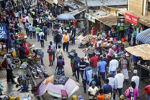 FILE - In this March 24, 2020, file photo, residents walk through a small and crowded market where social-distancing is difficult, in the Mathare slum, or informal settlement, of Nairobi, Kenya. The new coronavirus causes mild or moderate symptoms for most people, but for some, especially older adults and people with existing health problems, it can cause more severe illness or death. (AP Photo/Brian Inganga, File)