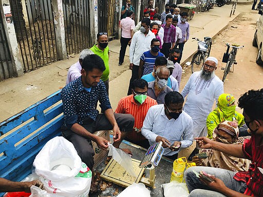 FILE - In this March 25, 2020, file photo, people line up to shop for essential items from a roadside truck in Dhaka, Bangladesh. In Dhaka, a city of more than 10 million where the average home is less than 120 square feet and a million people live in slums, social distancing is easier said than done. (AP Photo/Al-emrun Garjon)