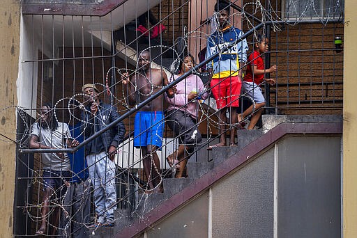 In this March 27, 2020, photo, residents of the densely populated Hillbrow neighborhood of downtown Johannesburg, confined in an attempt to prevent the spread coronavirus, stand on a staircase. South Africa went into a nationwide lockdown for 21 days in an effort to mitigate the spread to the coronavirus. (AP Photo/Jerome Delay)