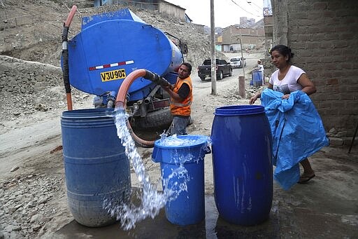 FILE - In this March 13, 2020, file photo, a worker fills a container with water from a water truck at the Villa Maria del Triunfo shantytown in Lima, Peru. The poor who live in the hills of Peru's capital, for whom a basic supply of clean water is a daily struggle, are finding it hard to meet the basic hygiene recommendations by health officials to avoid contracting the new coronavirus: Wash your hands for at least 20 seconds. (AP Photo/Martin Mejia, File)