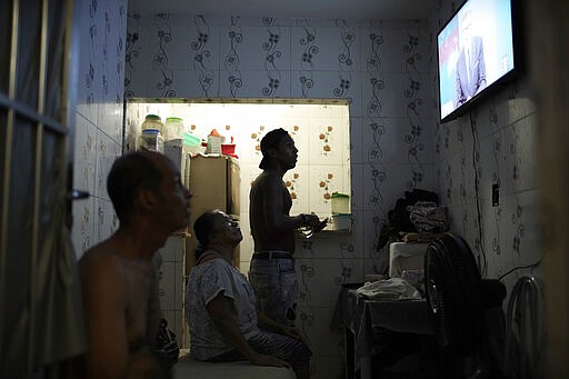 In this March 20, 2020 photo, Gloria Felismino da Silva, center, sits with her family to watch the news in their window-less home in the Rocinha slum of Rio de Janeiro, Brazil, amid the spread of the new coronavirus. As the virus spreads, the World Health Organization has pointed out that the future of the pandemic will be determined by what happens in some of the world&#146;s poorest and most densely populated countries. From Mumbai to Rio de Janeiro to Johannesburg the question is: What do you do if there is no space to socially distance yourself from others in some of world&#146;s most unequal regions? (AP Photo/Silvia Izquierdo)