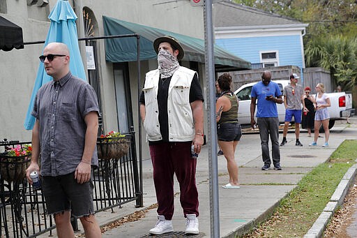 Service and entertainment industry employees who have been laid off due to the new coronavirus pandemic, exercise social distancing as they line up for meals cooked by chef Isaac Toups at his restaurant Toups Meatery in New Orleans, Friday, March 27, 2020. While rich in history and culture, New Orleans is economically poor, and the people here are not necessarily well-positioned to weather this latest storm. (AP Photo/Gerald Herbert)