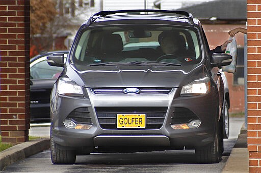 A patron picks up a sandwich from a drive-thru window at a shop where the indoor dining area is closed in efforts to slow the spread of COVID-19, Wednesday, March 18, 2020, in Evans City, Pa. (AP Photo/Keith Srakocic)