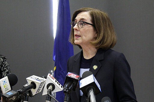 FILE - In this Monday, March 16, 2020 file photo, Gov. Kate Brown speaks at a news conference to announce a four-week ban on eat-in dining at bars and restaurants throughout the state in Portland, Ore., to slow the spread of the new coronavirus. &#147;I am gravely concerned about our ability to deliver basic services over the next six months to a year given the drop in revenues, and that&#146;s why I am encouraging the Legislature to be extremely fiscally prudent,&#148; Brown, a Democrat, said about building the budget for the coming fiscal year. (AP Photo/Gillian Flaccus)