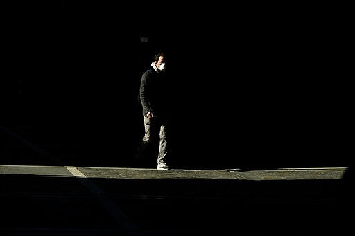 A pedestrian walks wearing mask protection against the spread of coronavirus, in Pamplona, northern Spain, Friday, March 27, 2020. (AP Photo/Alvaro Barrientos)