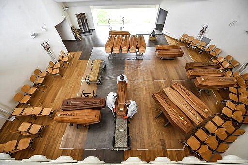 Coffins arriving from the Bergamo area, where the coronavirus infections caused many victims, are being unloaded from a military truck that transported them in the cemetery of Cinisello Balsamo, near Milan in Northern Italy, Friday, March 27, 2020.  The new coronavirus causes mild or moderate symptoms for most people, but for some, especially older adults and people with existing health problems, it can cause more severe illness or death.  (Claudio Furlan/LaPresse via AP)