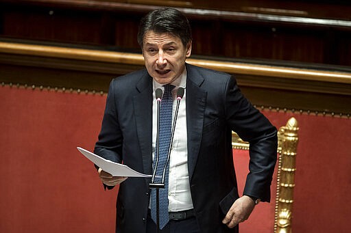 Italian Premier Giuseppe Conte adjusts his jacket as he refers to parliament on the ongoing Covid-19 situation, in Rome, Thursday, March 26, 2020. After more than two weeks of a nationwide lockdown to halt the spread of the coronavirus, the Italian government decided to expand the mandatory closure of nonessential commercial activities to heavy industry in the eurozone's third-largest economy, a major exporter of machinery, textiles and other goods. The new coronavirus causes mild or moderate symptoms for most people, but for some, especially older adults and people with existing health problems, it can cause more severe illness or death.  (Roberto Monaldo/LaPresse via AP)