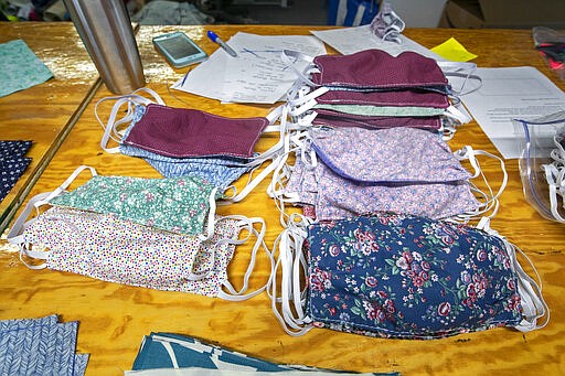 In this Monday, March 23, 2020, photo, cotton masks to be given to caregivers battling the coronavirus outbreak are stacked on a table at the North Sails shop in Freeport, Maine. The sail-maintenance business has converted part of its operation towards stitching masks instead of sails. (AP Photo/Robert F. Bukaty)