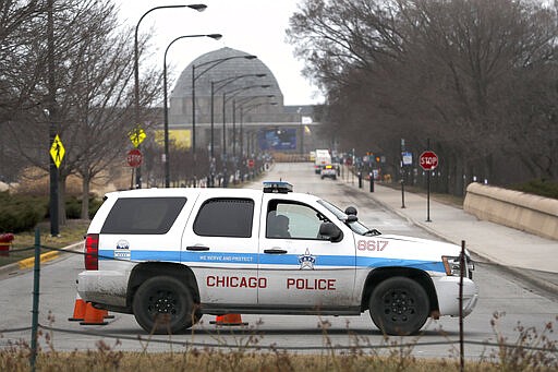 A Chicago police officer blocks the road to the Adler Planetarium along Lake Michigan Thursday, March 26, 2020, in Chicago. On Thursday morning, Chicago Police began turning joggers and others away from the city's lakefront trails amid fears of the spread of the coronavirus, hours after Mayor Lori Lightfoot threatened to shut them down if people would not stop crowding the areas. (AP Photo/Charles Rex Arbogast)