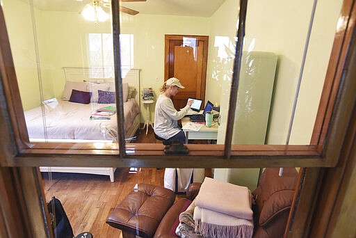 Lakeshore High School teacher Christy Sloan talks with one of her students about a reading assignment while working remotely from the spare bedroom of her home, St. Joseph, Mich., Friday, March 27, 2020. Teachers across the country are trying to come up with creative ways to keep their students engaged while working from home due to school closures from COVID-19. (Don Campbell/The Herald-Palladium via AP)