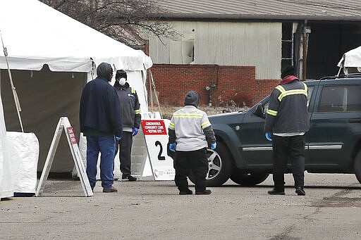 Health care officials watch as a vehicle approaches a testing site at the Michigan State Fairgrounds, Friday, March 27, 2020, in Detroit. The city set up several stations at the fairgrounds to allow for drive up testing for the coronavirus. (AP Photo/Carlos Osorio)