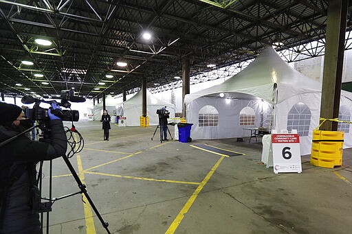 Journalists photograph the examination tents at the Michigan State Fairgrounds, Friday, March 27, 2020, in Detroit, where the city is preparing for coronavirus drive up testing. (AP Photo/Carlos Osorio)