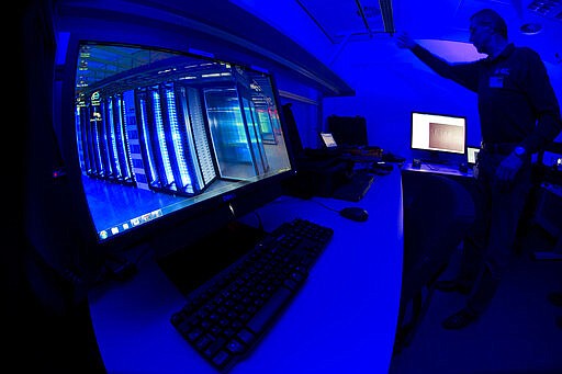 FILE - This Friday Jan. 11, 2013 file photo of a member of the Cybercrime Center as he turns on the light in a lab during a media tour at the occasion of the official opening of the Cybercrime Center at Europol headquarters in The Hague, Netherlands. Criminals have spotted a new business opportunity with the coronavirus pandemic and are now plundering the needy and the fearful and even disrupting the medical sector, online and off, with fraud, counterfeit products and cybercrime, a report issued Friday by the European law enforcement agency Europol says. (AP Photo/Peter Dejong, File)