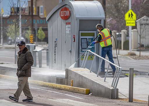 City crews clean a platform for the new ART bus system near Old Town Albuquerque, N.M., Wednesday, March 18, 2020. Normally this area is booming with tourists because of Spring Break but the recent pandemic has forced visitors to stay away.  (Roberto E. Rosales/The Albuquerque Journal via AP)