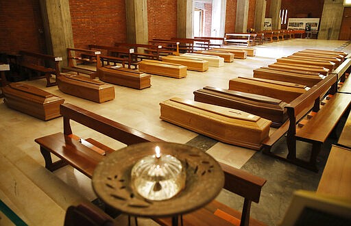 FILE - In this Thursday, March 26, 2020 file photo, coffins are lined up on the floor in the San Giuseppe church in Seriate, one of the areas worst hit by coronavirus, near Bergamo, Italy, waiting to be taken to a crematory. As the COVID-19 death toll mounts, faith leaders are grappling with a heart-wrenching question: How do you conduct a funeral in the midst of a global pandemic? (AP Photo/Antonio Calanni)