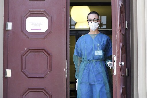 A staff member is standing in the doorway of the Corona Test Center of the University Medical Center in Rostock, Germany, Friday, March 27, 2020. The test centre is now also open on weekends. The new coronavirus causes mild or moderate symptoms for most people, but for some, especially older adults and people with existing health problems, it can cause more severe illness or death. (Bernd Wuestneck/dpa via AP)