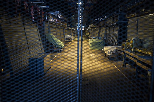 A view of La Boqueria market closed down in downtown Barcelona, Spain, Thursday, March 26, 2020. The new coronavirus causes mild or moderate symptoms for most people, but for some, especially older adults and people with existing health problems, it can cause more severe illness or death. (AP Photo/Emilio Morenatti)