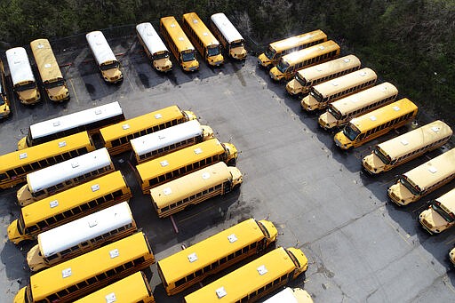 School buses sit unused in a parking lot Thursday, March 26, 2020, in St. Louis. All public and charter schools in Missouri are closed due to the coronavirus pandemic. (AP Photo/Jeff Roberson)