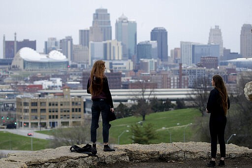 Two people adhere to social distancing as they view the downtown skyline, Thursday, March 26, 2020, in Kansas City, Mo. The city and surrounding counties are under a mandatory stay-at-home order to help stem the spread of the new coronavirus. (AP Photo/Charlie Riedel)