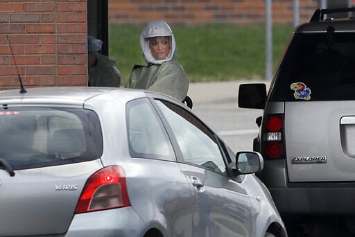 A Lawrence Memorial Hospital nurse works at a drive-thru virus testing facility In Lawrence, Kan., Thursday, March 26, 2020. Tests are by appointment only. The new coronavirus causes mild or moderate symptoms for most people, but for some, especially older adults and people with existing health problems, it can cause more severe illness or death. (AP Photo/Orlin Wagner)