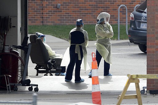 Lawrence Memorial Hospital personnel wait for the next patient to arrive for a drive-thru virus test In Lawrence, Kan., Thursday, March 26, 2020. Tests are by appointment only. The new coronavirus causes mild or moderate symptoms for most people, but for some, especially older adults and people with existing health problems, it can cause more severe illness or death. (AP Photo/Orlin Wagner)