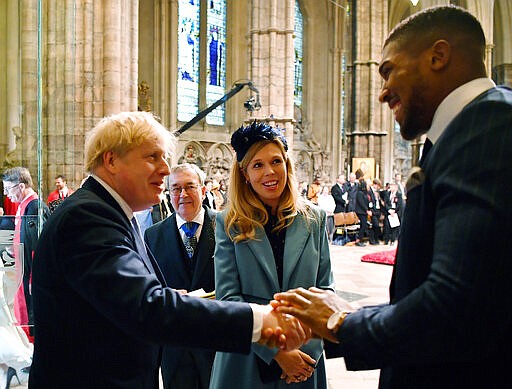 FILE - In this Monday March 9, 2020 file photo Britain's Prime Minister Boris Johnson and his fiancee partner Carrie Symonds talk with British boxer Anthony Joshua, right, as they leave after attending the annual Commonwealth Service at Westminster Abbey in London. British Prime Minister Boris Johnson has tested positive for the new coronavirus. Johnson's office said Friday March 27, 2020 that he was tested after showing mild symptoms, Downing St. says Johnson is self-isolating and continuing to lead the country's response to COVID-19. (Ben Stansall / Pool via AP, File)