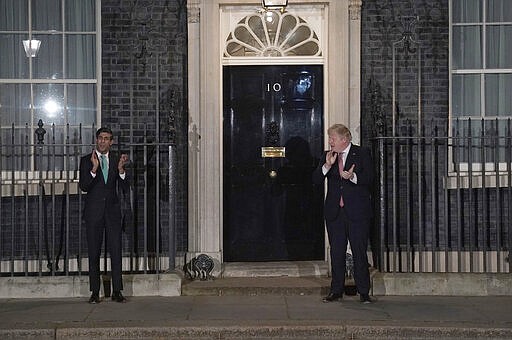 FILE - In this  Thursday March 26, 2020 file photo Britain's Prime Minister Boris Johnson outside 10 Downing Street in London as he joins a national applause to salute the health service (NHS) workers, in London. British Prime Minister Boris Johnson has tested positive for the new coronavirus. Johnson's office said Friday March 27, 2020 that he was tested after showing mild symptoms, Downing St. says Johnson is self-isolating and continuing to lead the country's response to COVID-19. (Aaron Chown/PA via AP)