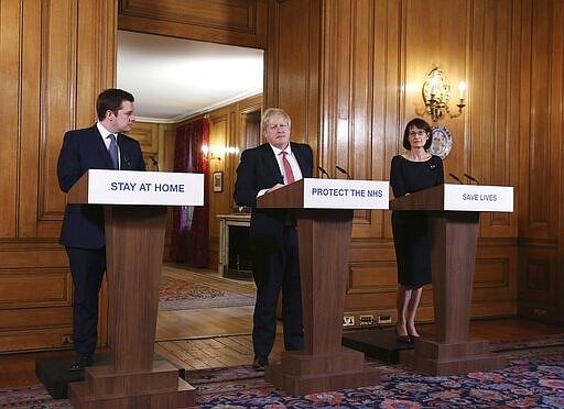 FILE - In this Sunday March 22, 2020 file photo Britain's Prime Minister Boris Johnson, is joined by Housing, Communities and Local Government Secretary Robert Jenrick, left, and Deputy Chief Medical Officer Jenny Harries, right,  during his daily COVID 19 coronavirus press briefing to announce new measures to limit the spread of the virus, at Downing Street in London.  British Prime Minister Boris Johnson has tested positive for the new coronavirus. Johnson's office said Friday March 27, 2020 that he was tested after showing mild symptoms, Downing St. says Johnson is self-isolating and continuing to lead the country's response to COVID-19.  (Ian Vogler / Pool via AP, File)