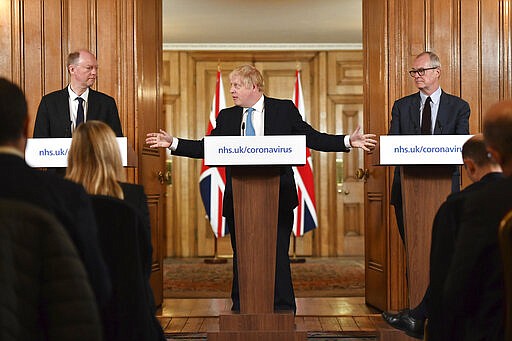 FILE  - In this Thursday, March 19, 2020 file photo Britain's Prime Minister Boris Johnson, centre, gestures to Chief Medical Officer Professor Chris Whitty, left and Chief Scientific Adviser Patrick Vallance, during a coronavirus news conference at 10 Downing Street, in London. British Prime Minister Boris Johnson has tested positive for the new coronavirus. Johnson's office said Friday March 27, 2020 that he was tested after showing mild symptoms, Downing St. says Johnson is self-isolating and continuing to lead the country's response to COVID-19. (Leon Neal/Pool Photo via AP)