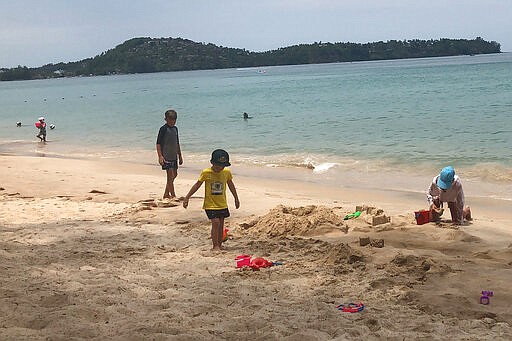 In this March 26, 2020, photo, tourists play on a beach in Phuket, Thailand. Tourists across Asia are finding their dream vacations have turned into travel nightmares as airlines cancel flights and countries close their borders in the fight against the coronavirus pandemic. (AP Photo/Penny Wang)