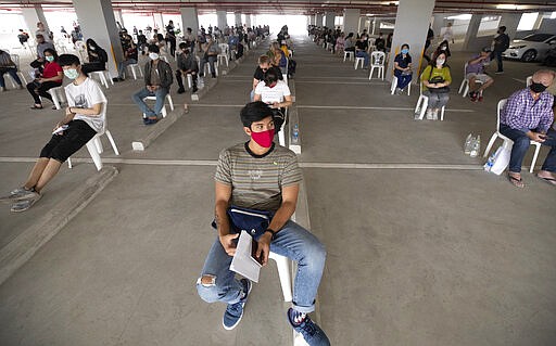 Tourists practice social distancing as they wait to extend their visa at Immigration Bureau in Bangkok, Thailand, Friday, March 27, 2020. Tourists across Asia are finding their dream vacations have turned into travel nightmares as airlines cancel flights and countries close their borders in the fight against the coronavirus pandemic. (AP Photo/Sakchai Lalit)