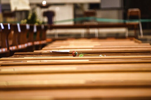 In this Thursday, March 26, 2020 photo, a red rose lies on a coffin lined up along others inside the San Giuseppe church in Seriate, one of the areas worst hit by coronavirus, near Bergamo, Italy, mark spaces where coffins are to be placed before being taken to a crematory. Italy is seeing a slight stabilizing in its confirmed coronavirus infections two weeks into the world&#146;s most extreme nationwide shutdown, but the virus is taking its silent spread south after having ravaged the health care system in the north. The new coronavirus causes mild or moderate symptoms for most people, but for some, especially older adults and people with existing health problems, it can cause more severe illness or death.  (Claudio Furlan/LaPresse via AP)