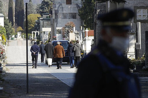 FILE - In this Tuesday, March 17, 2020. filer, relatives walk behind a hearse carrying a coffin inside the Monumentale cemetery, in Bergamo, the heart of the hardest-hit province in Italy&#146;s hardest-hit region of Lombardy, Italy.  Italy is seeing a slight stabilizing in its confirmed coronavirus infections two weeks into the world&#146;s most extreme nationwide shutdown, but the virus is taking its silent spread south after having ravaged the health care system in the north. The new coronavirus causes mild or moderate symptoms for most people, but for some, especially older adults and people with existing health problems, it can cause more severe illness or death. (AP Photo/Luca Bruno, File)