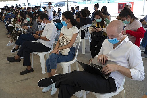 Tourists practice social distancing as they wait to extend their visa at Immigration Bureau in Bangkok, Thailand, Friday, March 27, 2020. Tourists across Asia are finding their dream vacations have turned into travel nightmares as airlines cancel flights and countries close their borders in the fight against the coronavirus pandemic. (AP Photo/Sakchai Lalit)