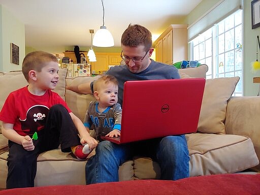 This image released by Caren Tolleth shows her husband Michael posing with their sons Gavin, 5, left, and Emmett, 9 months, at their home in Gillette, N.J. The coronavirus outbreak is having an impact on couples and their relationships. Some stay-at-home mothers say their husbands, now homebound, are finally having to see how much domestic work their spouses do.  (Caren Tolleth via AP)