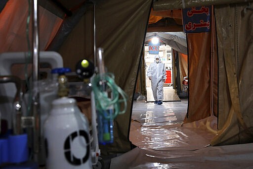 A person in protective clothing walks through a temporary 2,000-bed hospital for COVID-19 coronavirus patients set up by the Iranian army at the international exhibition center in northern Tehran, Iran, on Thursday, March 26, 2020. (AP Photo/Ebrahim Noroozi)