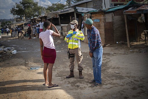 A South African police officer speaks to residents of the densely populated Alexandra township east of Johannesburg Friday, March 27, 2020. South Africa went into a nationwide lockdown for 21 days in an effort to mitigate the spread to the coronavirus, but in Alexandra, many people were gathering in the streets disregarding the lockdown. The new coronavirus causes mild or moderate symptoms for most people, but for some, especially older adults and people with existing health problems, it can cause more severe illness or death.(AP Photo/Jerome Delay)