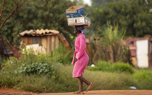 A woman carrying boxes on her head at a informal settlement, east of Johannesburg, South Africa, Friday, March 27, 2020. (AP Photo/Themba Hadebe)